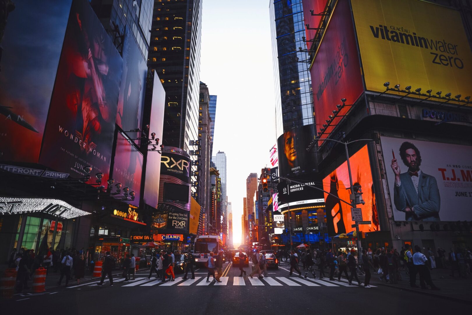 Dusk descends on a bustling times square with vivid billboards and busy streets.