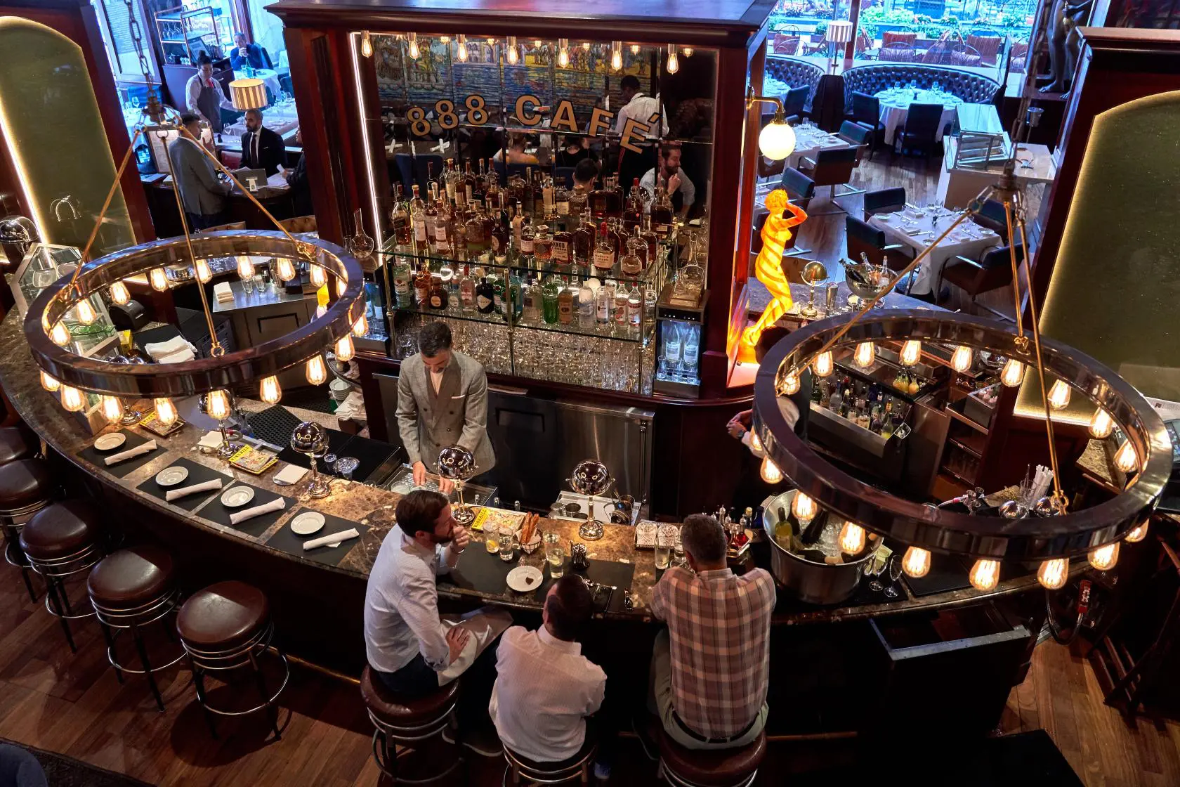 Elevated view of a bustling circular bar with patrons and bartender in a luxury atmospheric setting.