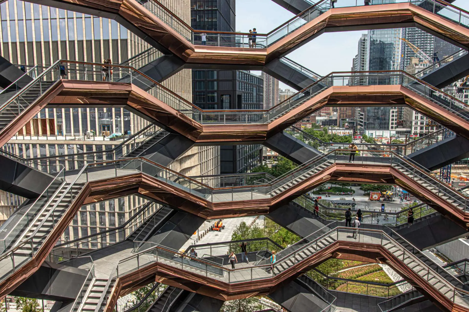 An architectural view of the vessel's intricate honeycomb-like structure with multiple intersecting staircases, against a Manhattan urban backdrop.